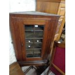 A 71cm antique oak two part corner cabinet on stand with shelves enclosed by a beaded glazed panel