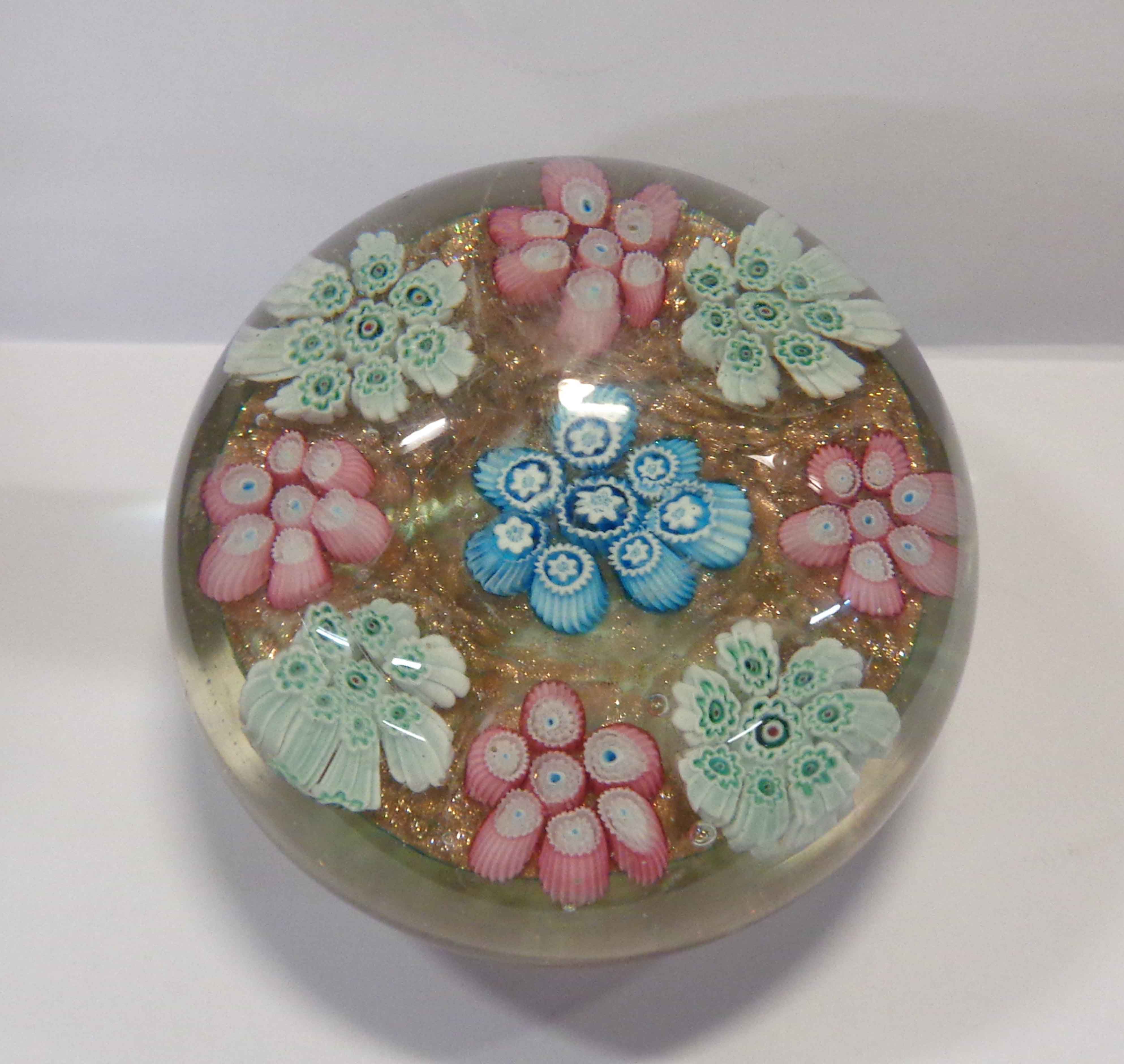 A vintage Murano glass paperweight with cluster millefiori decoration on an aventurine ground