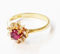 A marked 14k yellow metal ring, set with central small ruby within a diamond border - size K 1/2