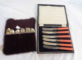 A cased set of six 1930's silver plated butter knives with pink coral coloured composite handles -
