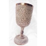 A 17.5cm high Anglo-Indian white metal goblet with profuse embossed foliate scroll and perching