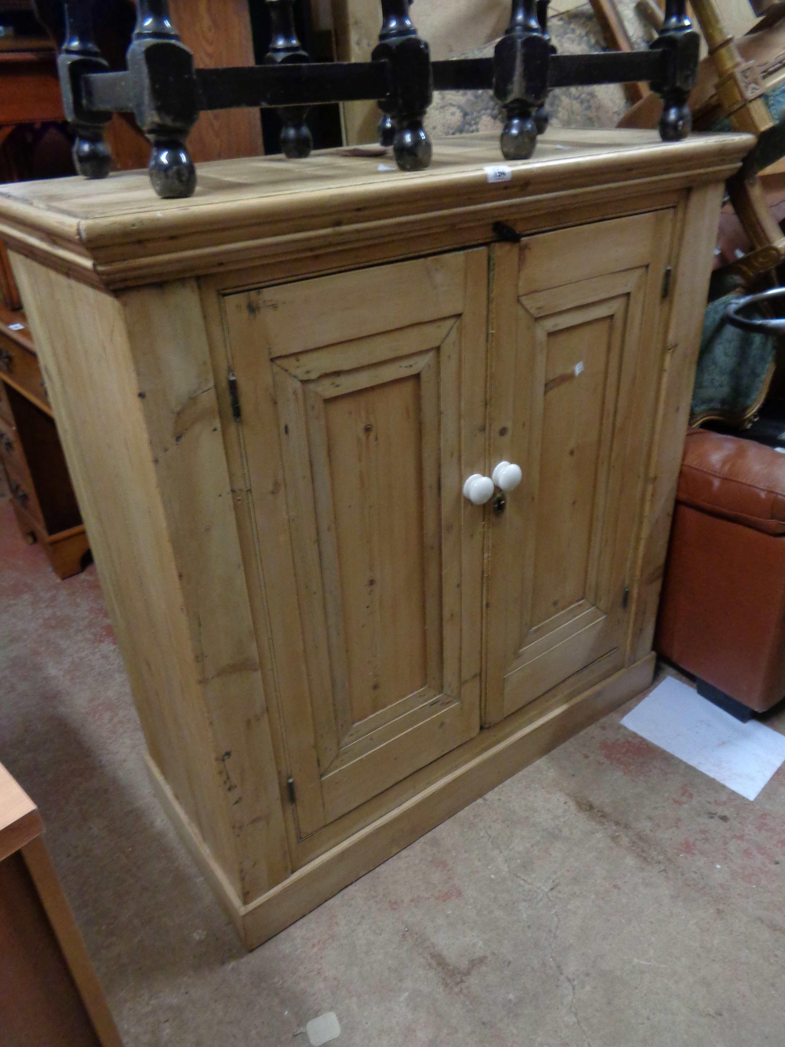 A 1.07m antique stripped pine two door cupboard with shelves enclosed by a pair of panelled doors,