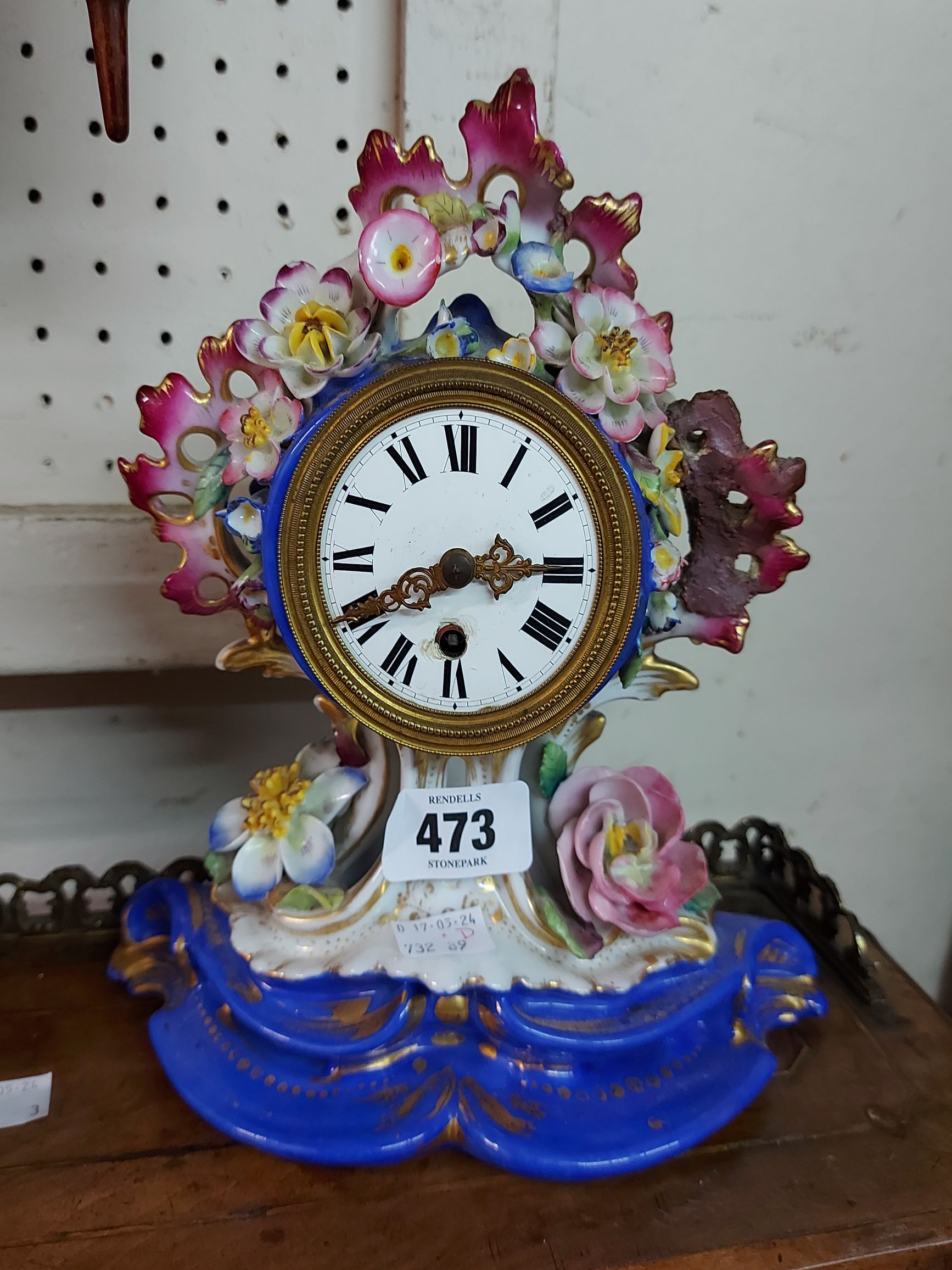 A small 19th Century ornate porcelain cased timepiece with floral encrusted decoration and simple