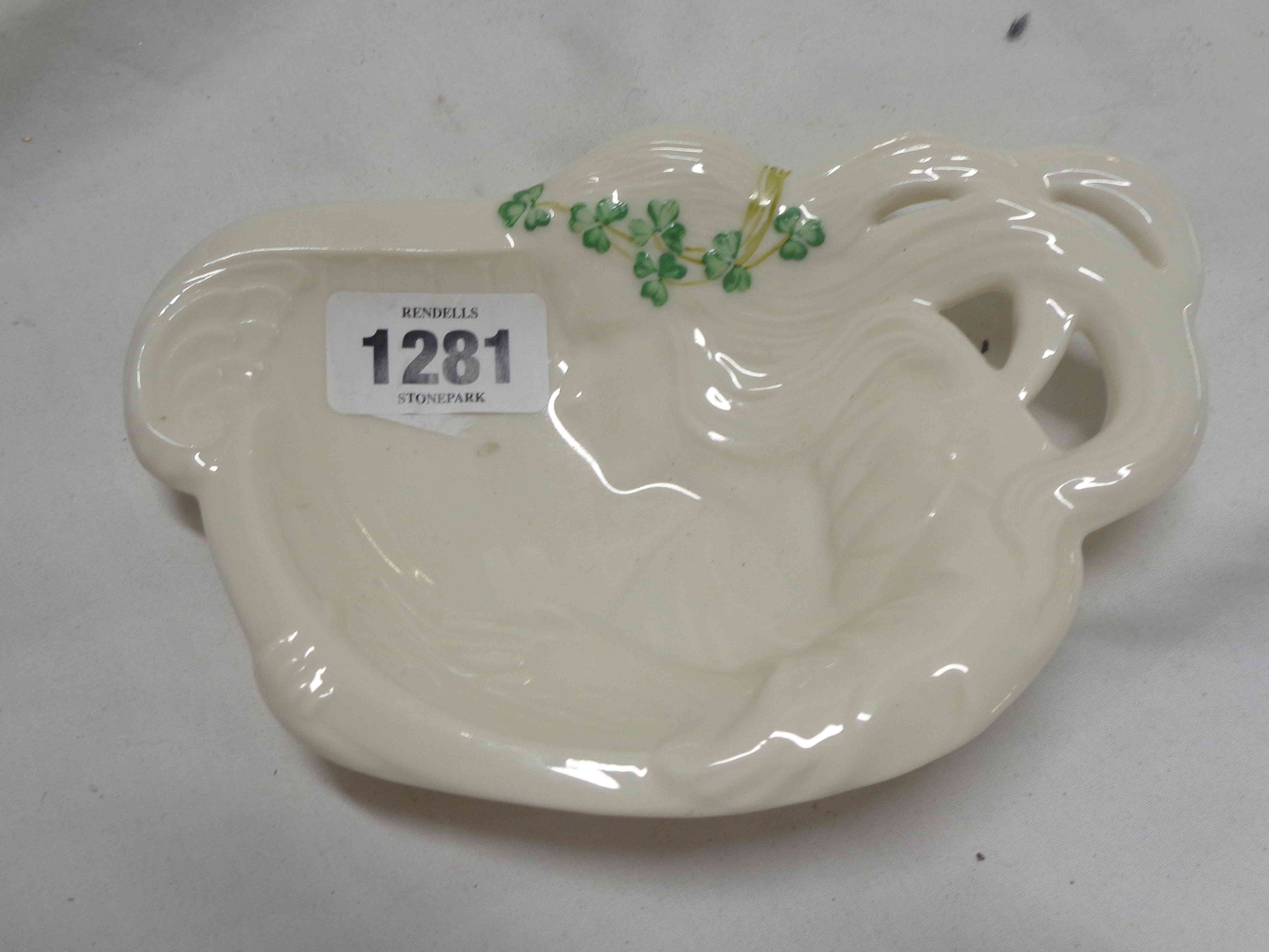 A Belleek porcelain dish in the form of an Art Nouveau style maiden with green painted shamrock