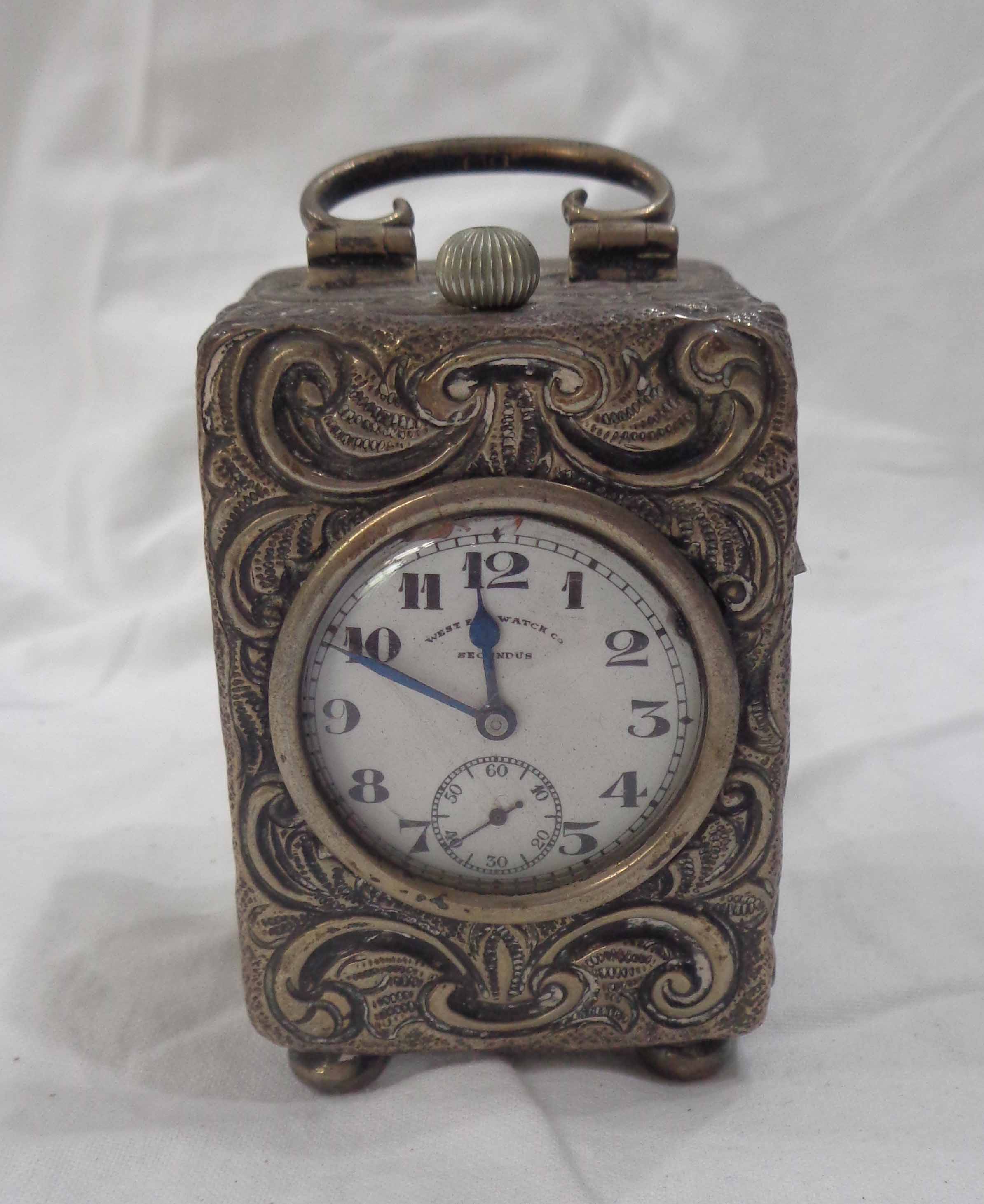 A small silver traveling timepiece case with scroll handle and profuse embossed decoration -