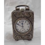 A small silver traveling timepiece case with scroll handle and profuse embossed decoration -