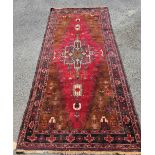 A vintage Persian handmade wool runner with decorative border on red ground - 2.5m X 1.15m