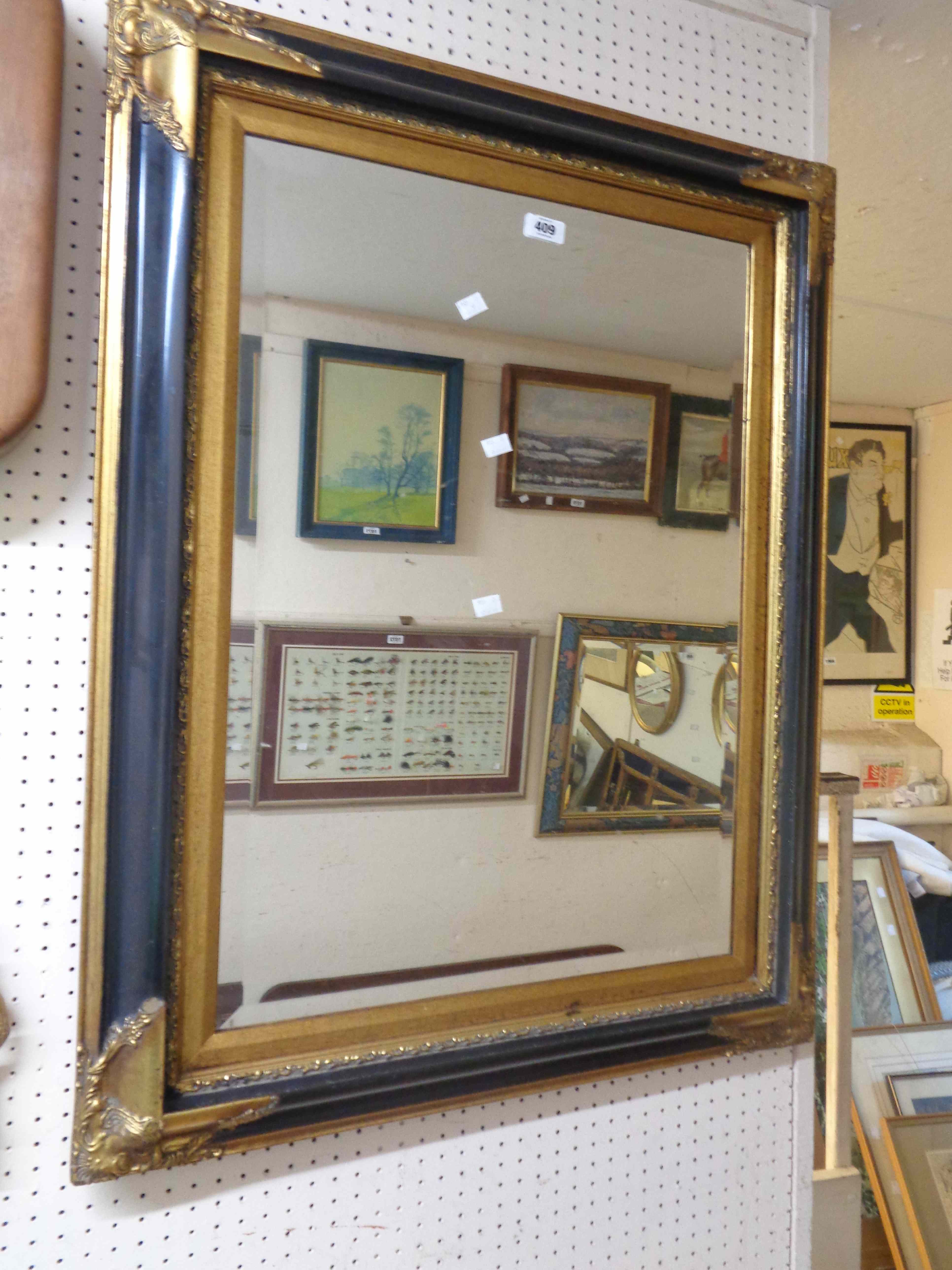 A large reproduction ebonised and parcel gilt framed bevelled oblong wall mirror