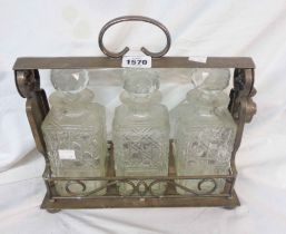 An old silver plated three bottle tantalus with pierced scroll base and three part hobnail cut glass