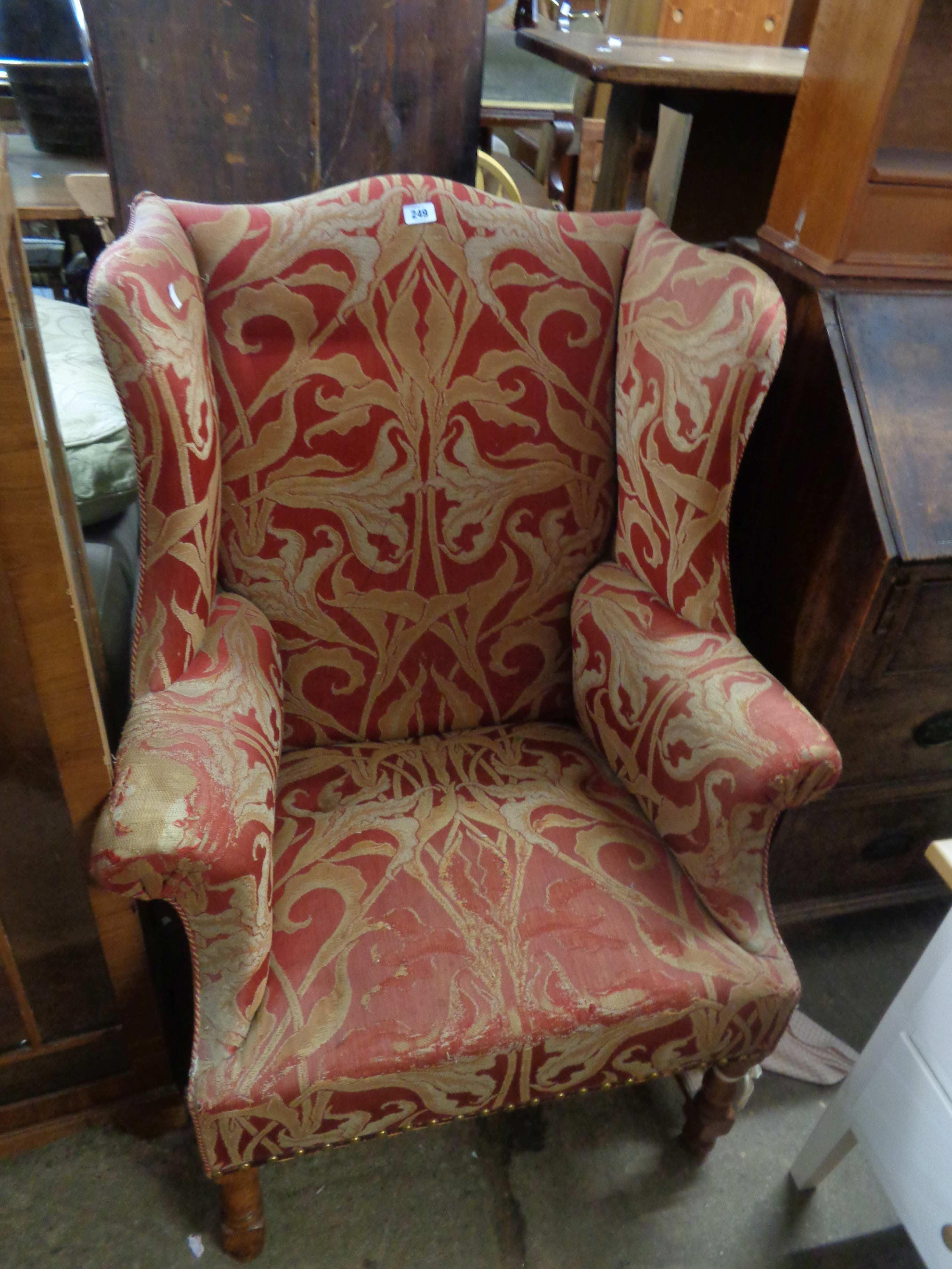 A 19th Century wingback armchair with red and gold foliate tapestry upholstery, set on turned