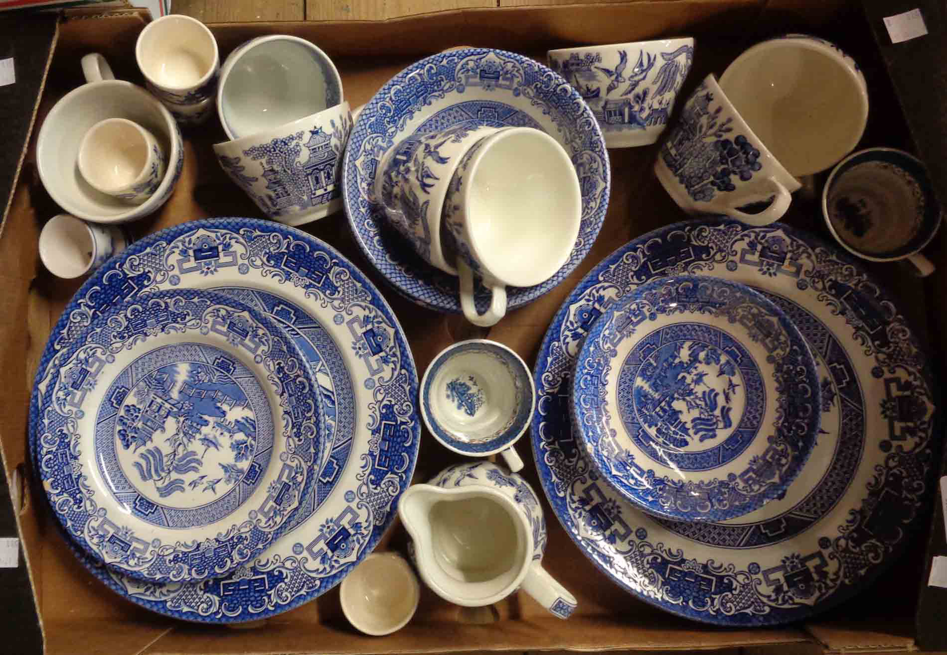 A box containing a quantity of blue and white Willow pattern tableware