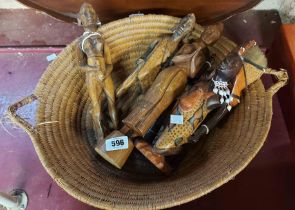 A hand woven basket containing three carved wooden African figures and an oriental carved woman