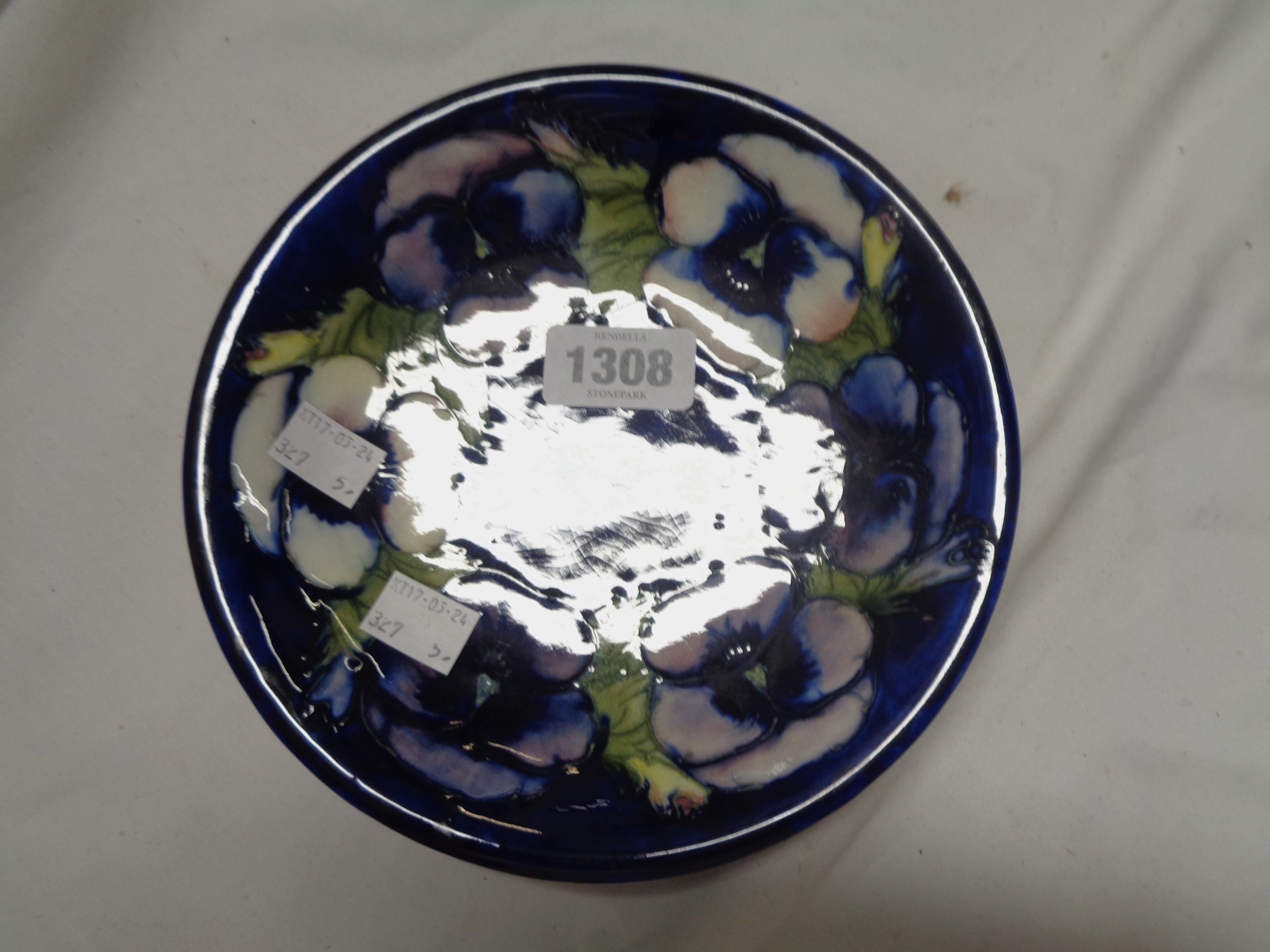 A Moorcroft pottery plate, decorated with a tube-lined floral pattern on a blue ground - chip to
