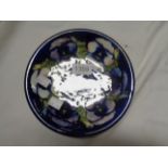 A Moorcroft pottery plate, decorated with a tube-lined floral pattern on a blue ground - chip to