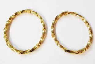 A pair of yellow metal twist bracelets with sprung hinges