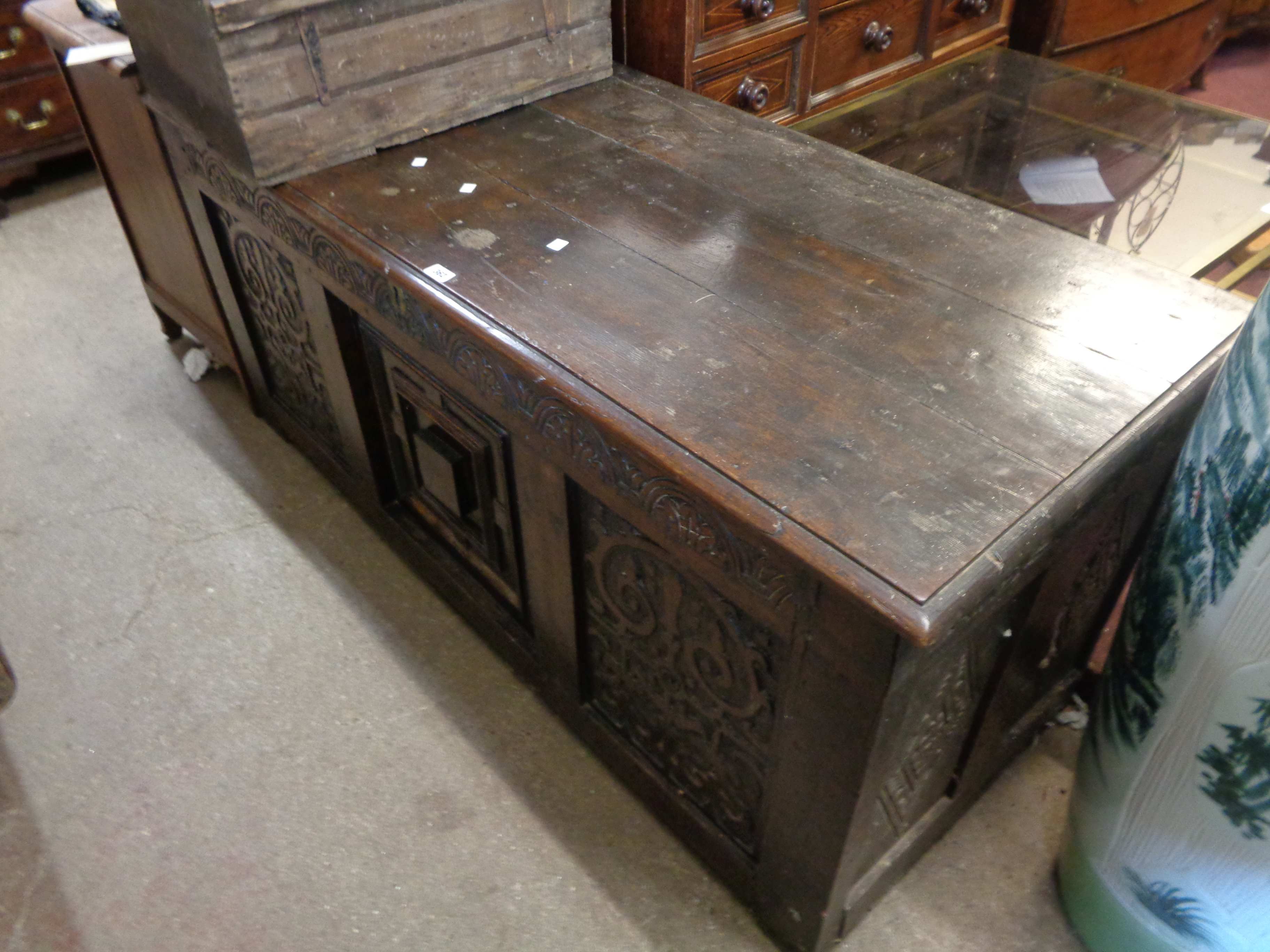 A 1.52m 18th Century oak three panel coffer with iron strap hinges to the lift-top and carved