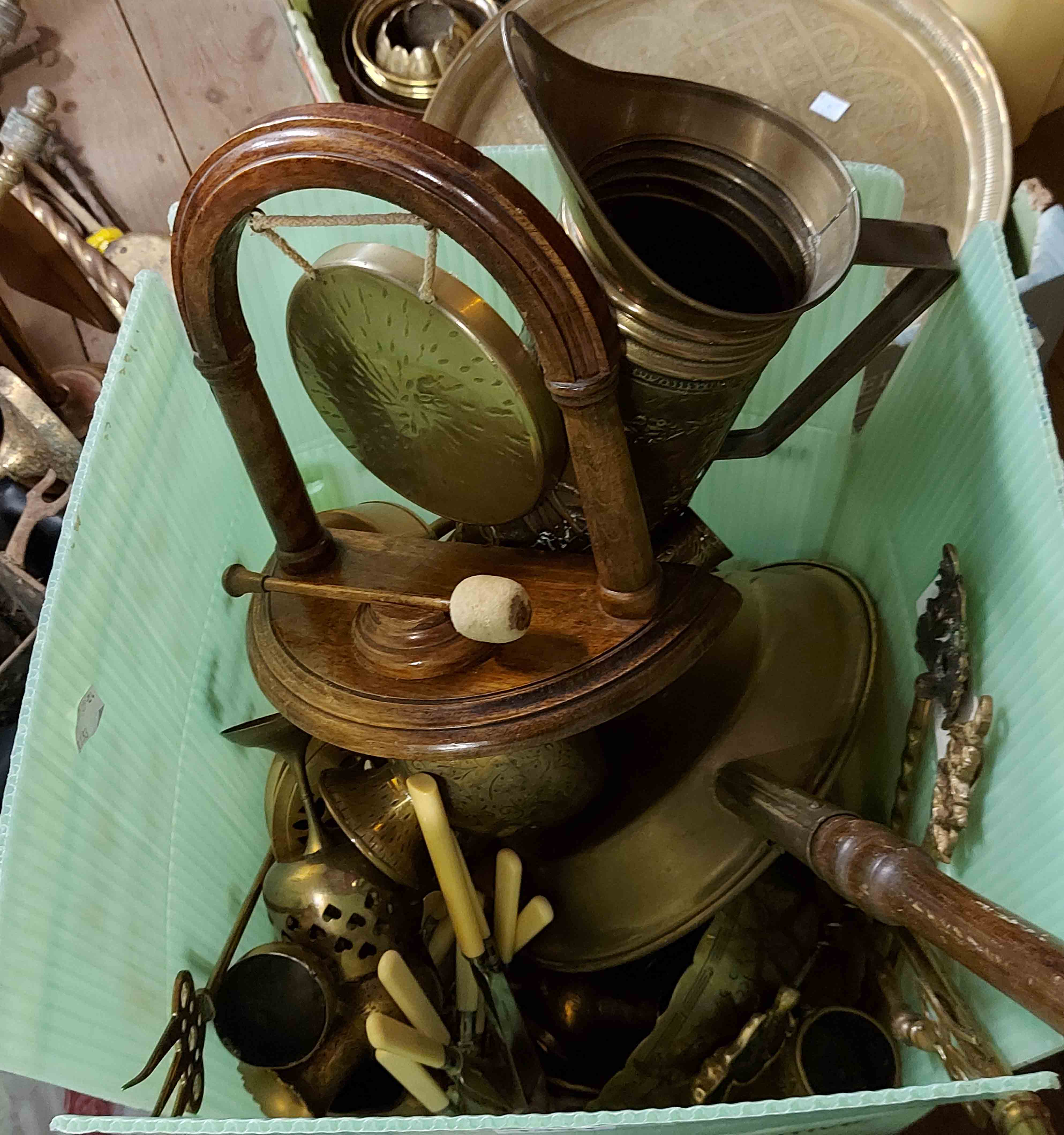 A green crate containing a quantity mixed brassware including gong on stand, bed warmer, EPNS