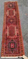 A vintage Persian wool runner with repeat motifs on a pale red ground