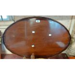 An antique mahogany tray with scalloped rim and brass handle