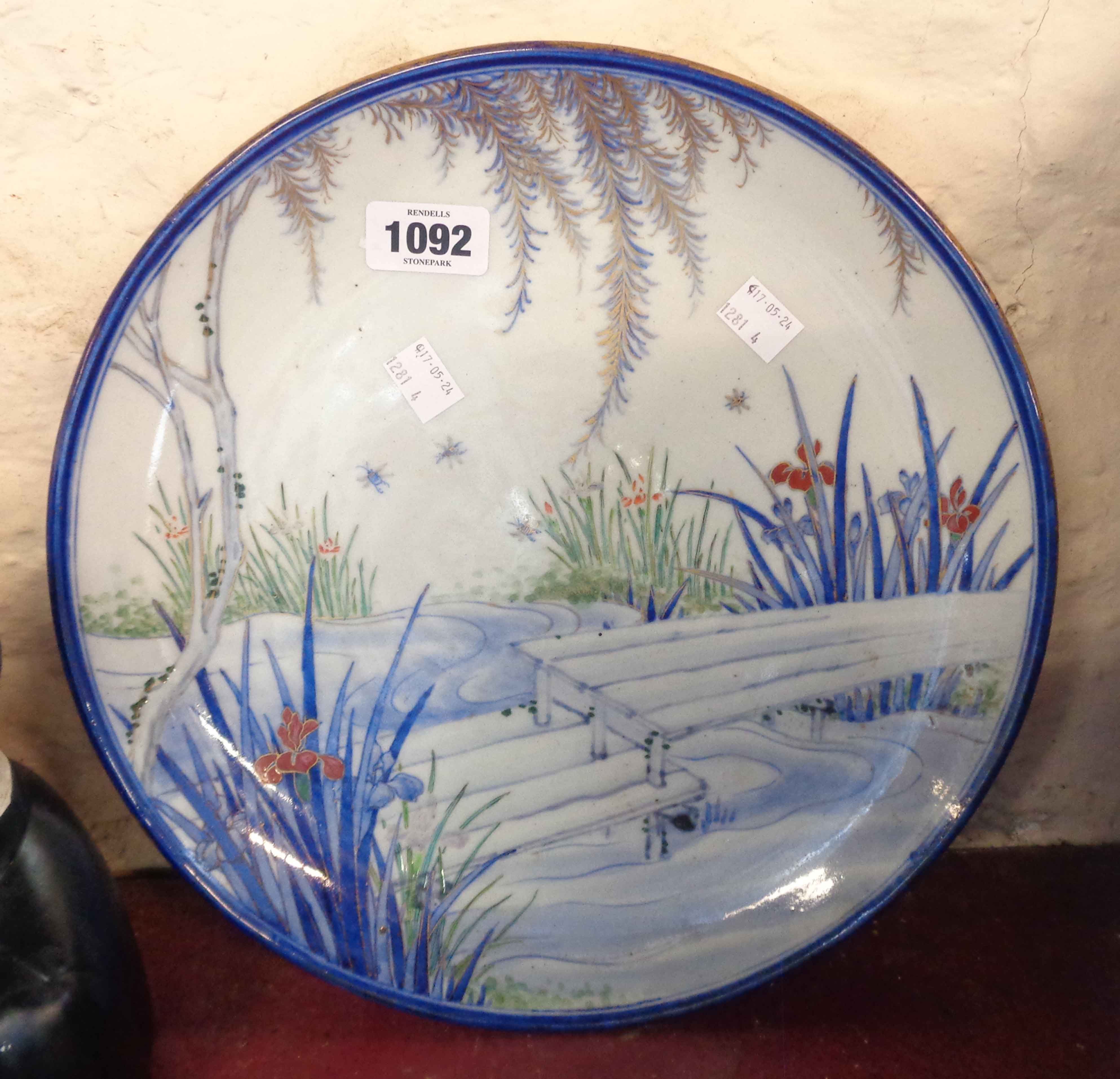 An antique Japanese porcelain charger with painted and gilt decoration, depicting a garden pond -