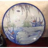 An antique Japanese porcelain charger with painted and gilt decoration, depicting a garden pond -