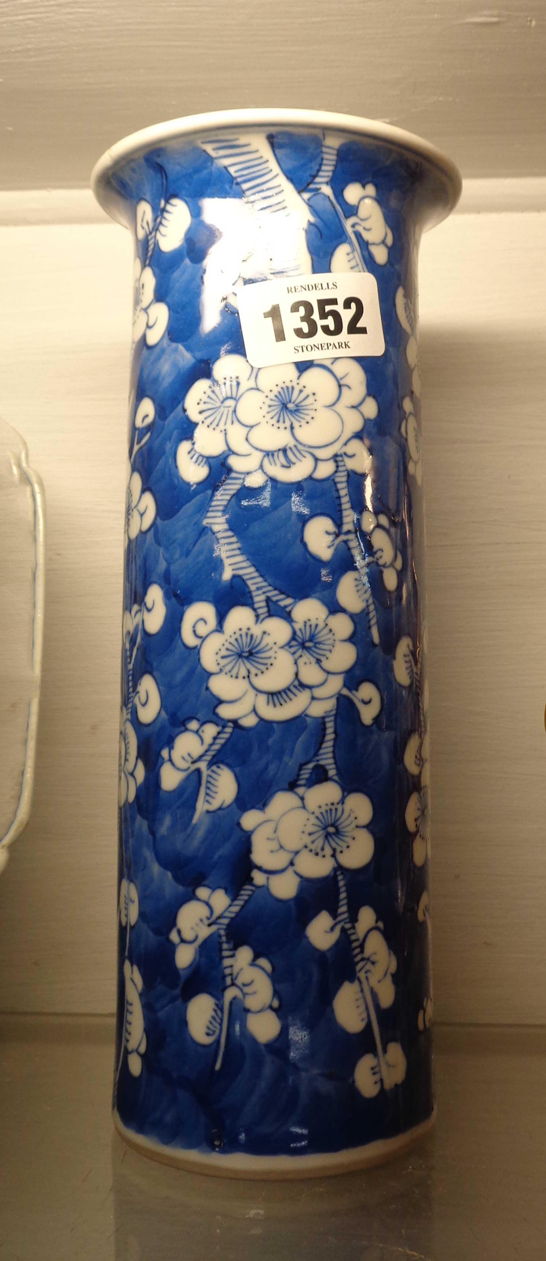 An antique Chinese porcelain vase of cylindrical form with a flared rim and hand painted prunus