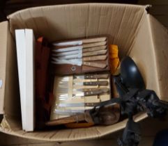 A box containing various kitchen items including steak knives, place mats, etc.