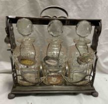 A vintage silver plated tantalus with scrolling foliate decoration containing three decanters each