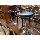 A pair of modern swivel kitchen stools with black leatherette upholstered seats, set on chrome