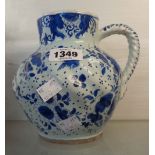 An antique Delft jug with wrythen form body, short neck and rope twist handle, decorated in blue