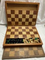 A wooden folding case containing an integral mixed wood chess board and a complete chess set -