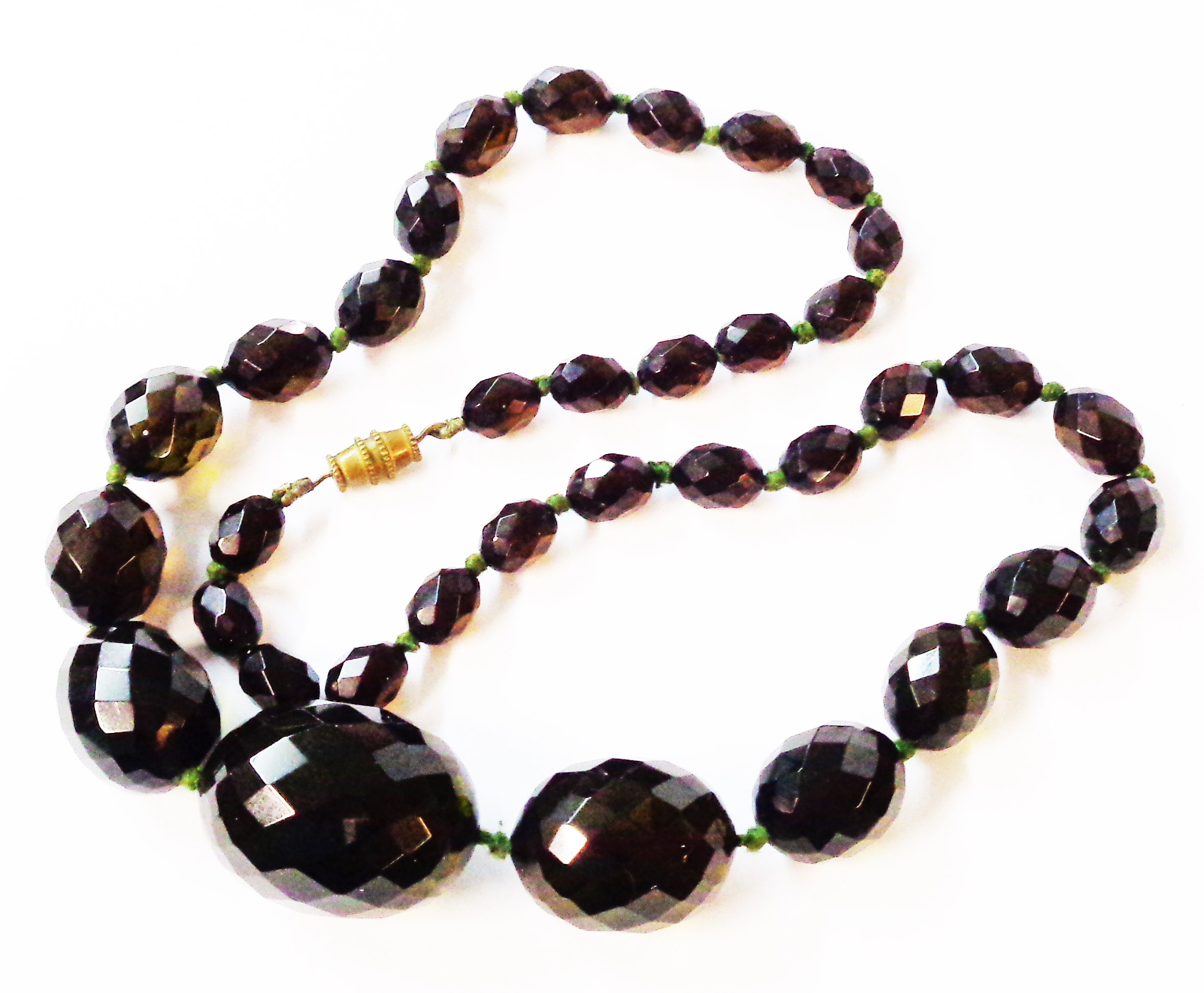 A vintage green amber faceted graduated bead necklace with plated barrel clasp