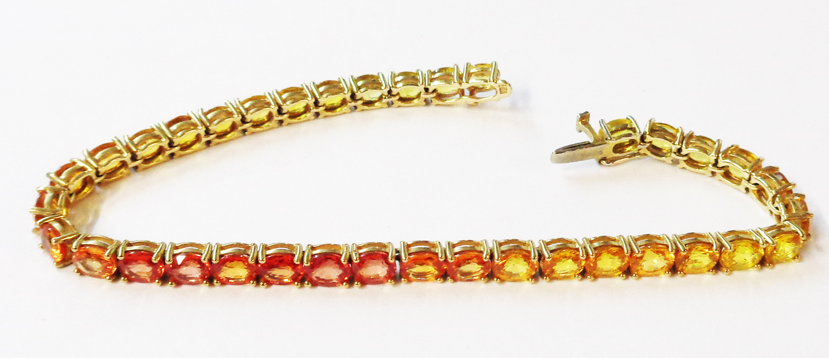 A 375 (9ct.) gold tennis/inline bracelet, each of the links set with an individual yellow, orange