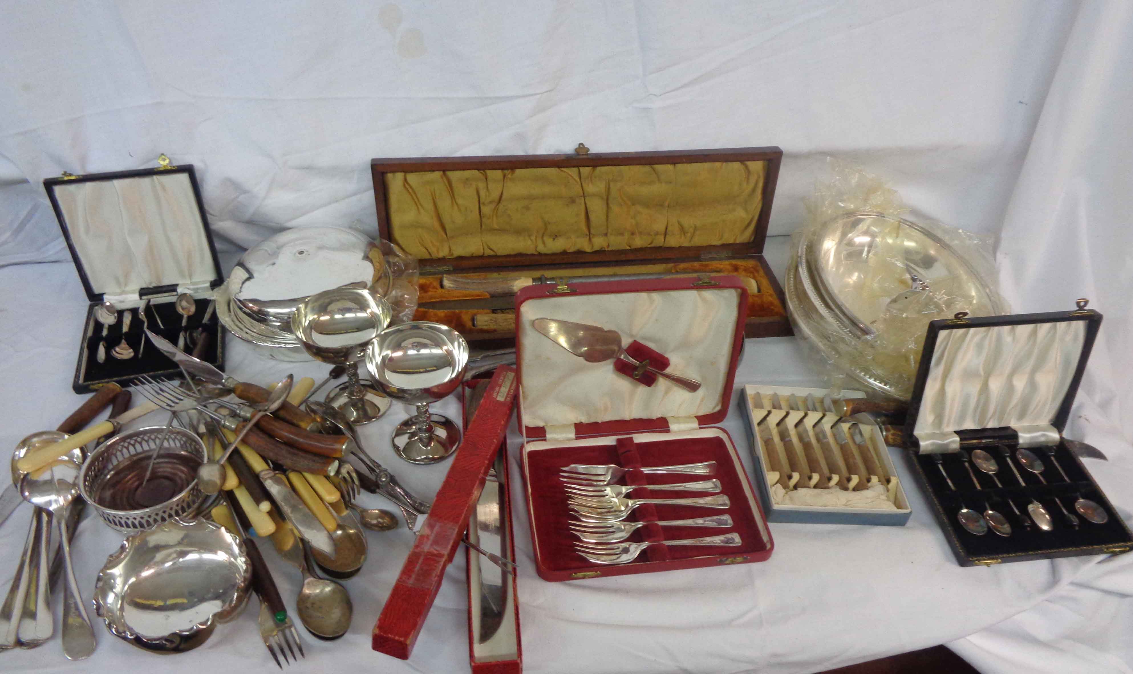 A box containing a quantity of silver plated items including entree dishes, cased and loose cutlery,