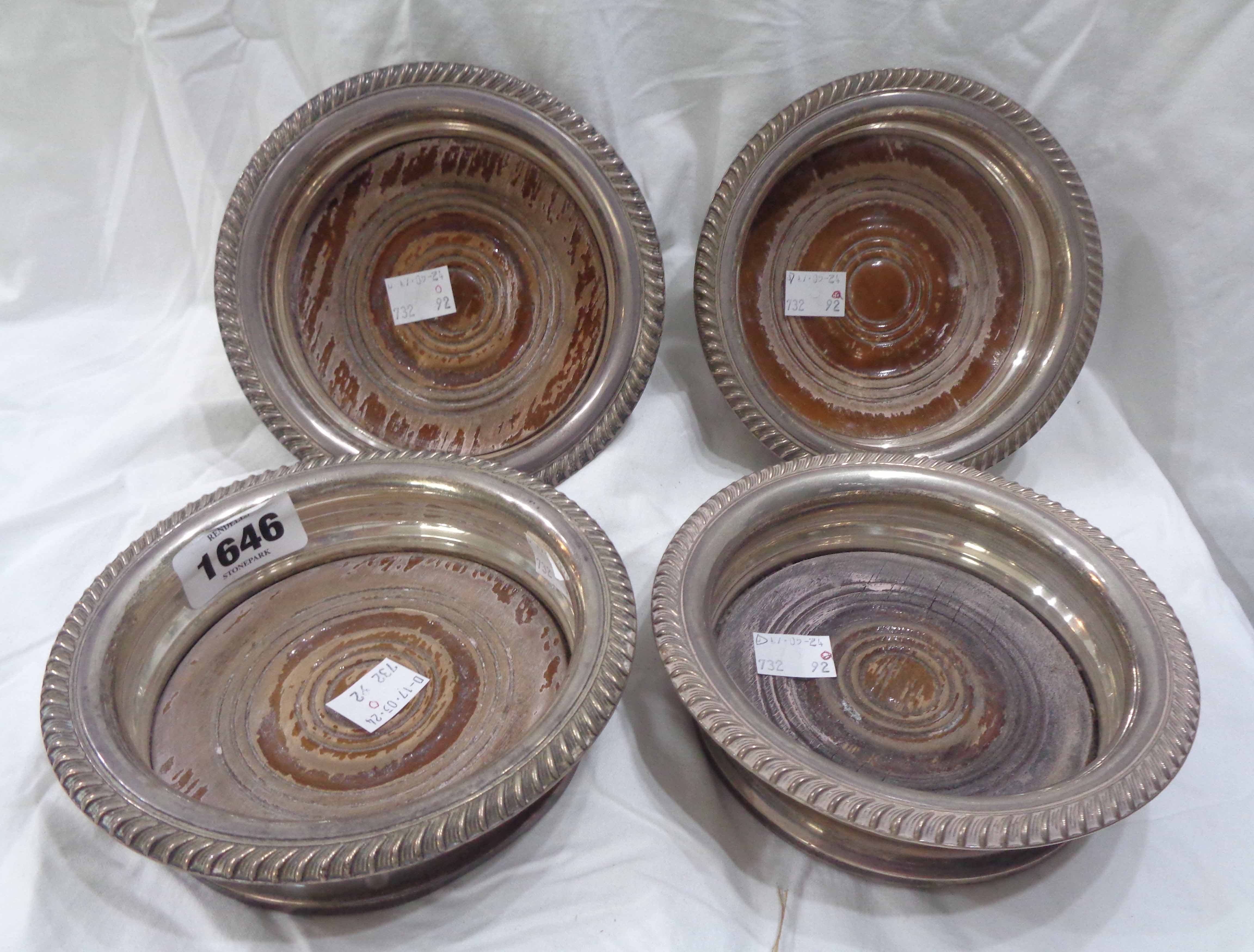 A set of four silver wine coasters with cast gadrooned rims and turned wood bases - marks worn,