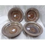 A set of four silver wine coasters with cast gadrooned rims and turned wood bases - marks worn,