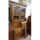 A 98cm Ercol dark elm two part wall unit with shelves enclosed by a pair of glazed panel doors and