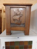 A vintage oak lift-top coal bin with carved galleon decoration and liner
