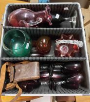 An aluminium flight case base containing a quantity of coloured glassware including cranberry, etc.