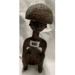 An African carved wood figure, depicting a man seated upon a stump with a large head piece - a/f