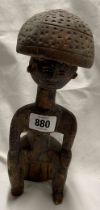 An African carved wood figure, depicting a man seated upon a stump with a large head piece - a/f