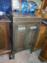 An old oak HMV gramophone cabinet with lift-top and drawers enclosed by a pair of panelled doors,