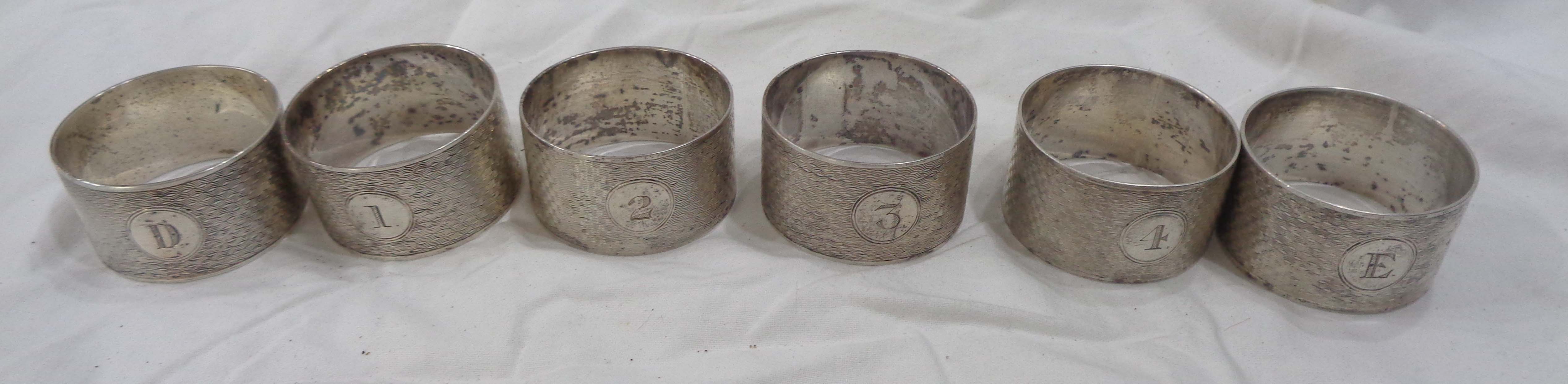 A set of six silver napkin rings with engine turned decoration, comprising four marked '1' to '4',