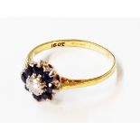 An import marked 750 (18ct.) gold ring, set with central diamond within a sapphire border - size L