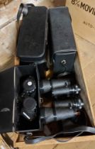 A wooden crate containing four pairs of binoculars and a Burgess vibro-tool