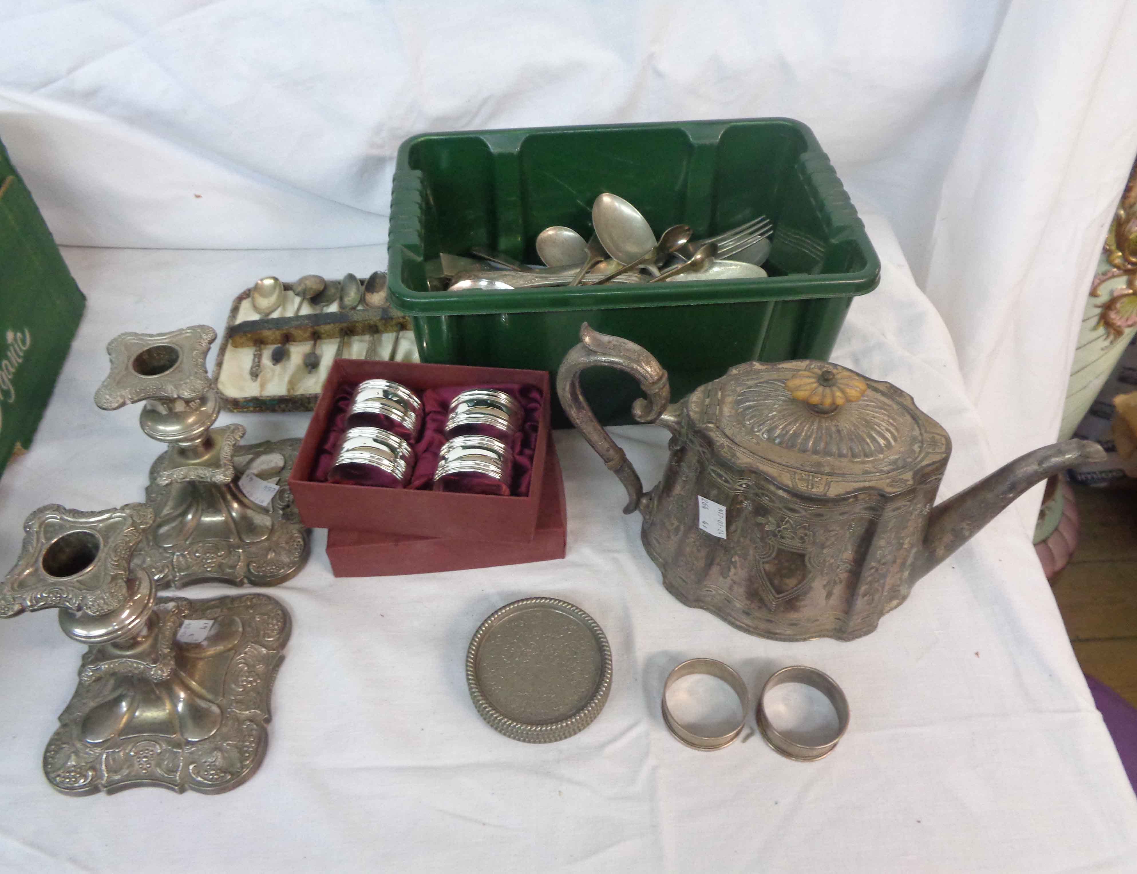 A box containing a silver plated teapot, a pair of candlesticks, a quantity of cutlery and two