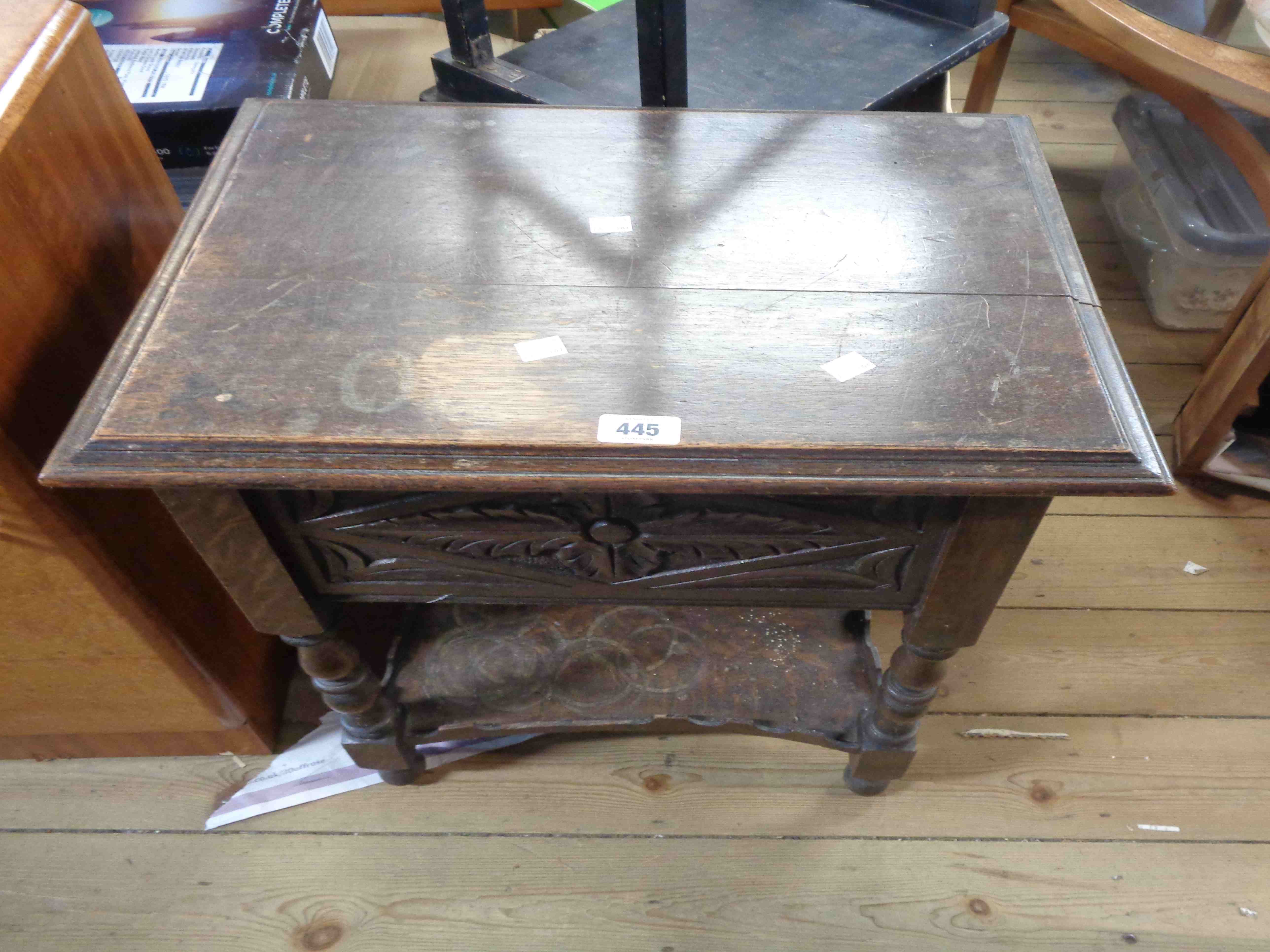 A 52cm antique carved oak lift-top box with pull-out partitioned interior, set on turned supports