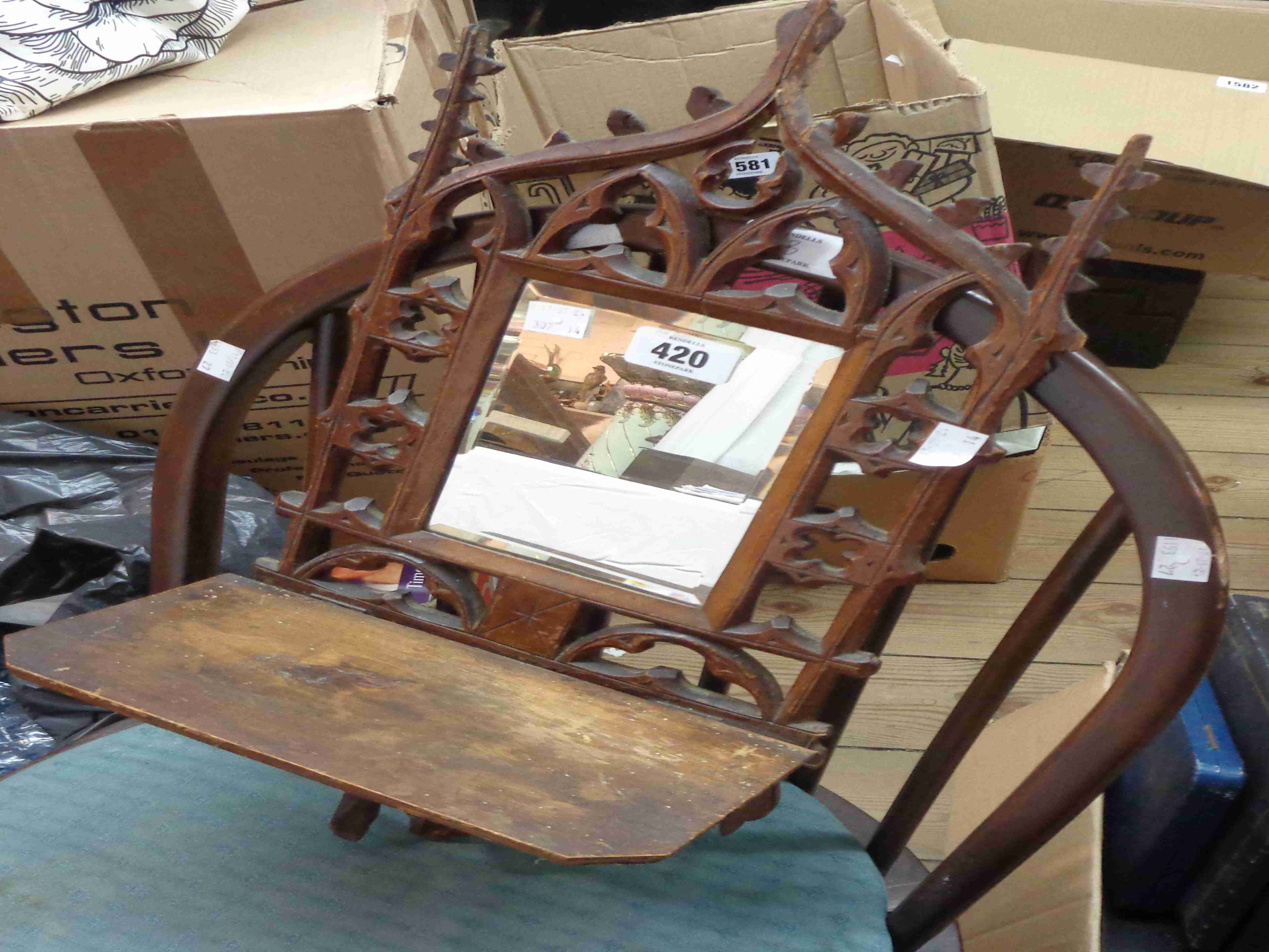 A small oblong wall mirror with ornate pierced Gothic framed and folding shelf under