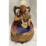 A small vintage figurine of an old lady seated upon a chair