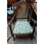 An early 20th Century stained mixed wood elbow chair with rattan back panel and overstuffed